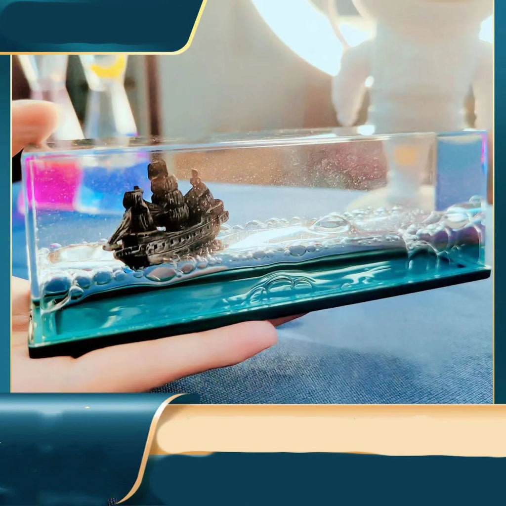 Fluid drift bottle with floating astronaut decoration in acrylic resin, black pearl pirate ship style, on a wooden desk.