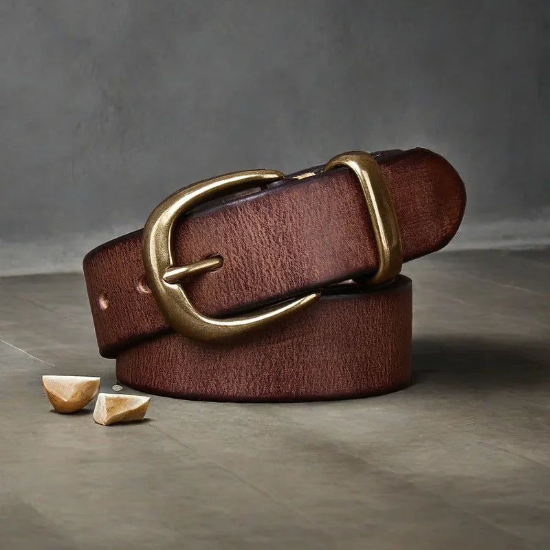 Men's black cattlehide leather jeans belt with a copper pin buckle on a wooden background.