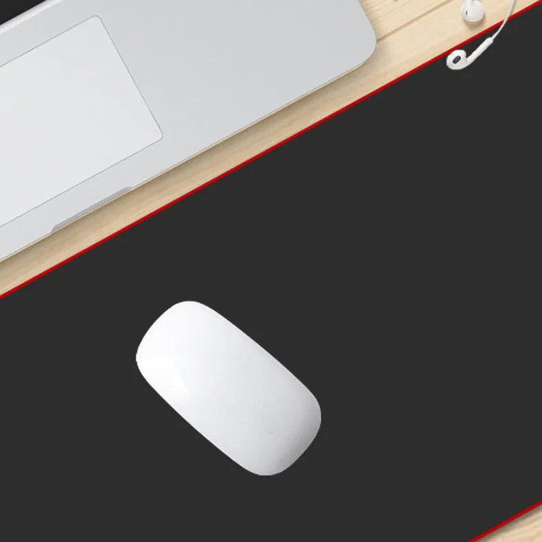 Long black desk pad with stitched edges on a wooden desk, with keyboard and mouse placed on top.