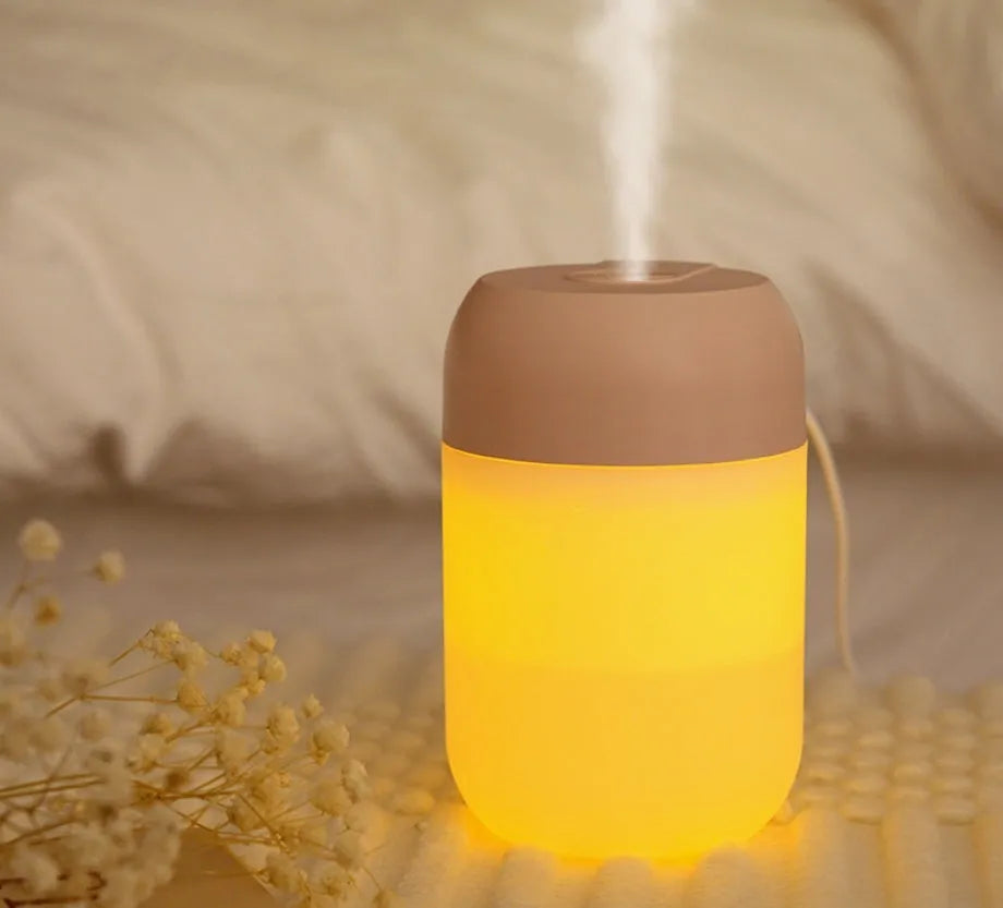 White cylindrical USB mini humidifier with charging cable on wooden desk