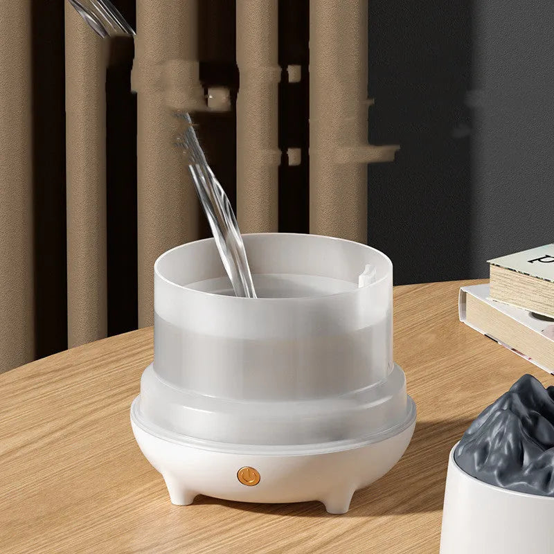 White volcano-shaped ultrasonic humidifier with USB cable on a wooden desk.