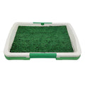 Green artificial grass indoor dog toilet tray with drainage holes and absorbent pads for puppy training.