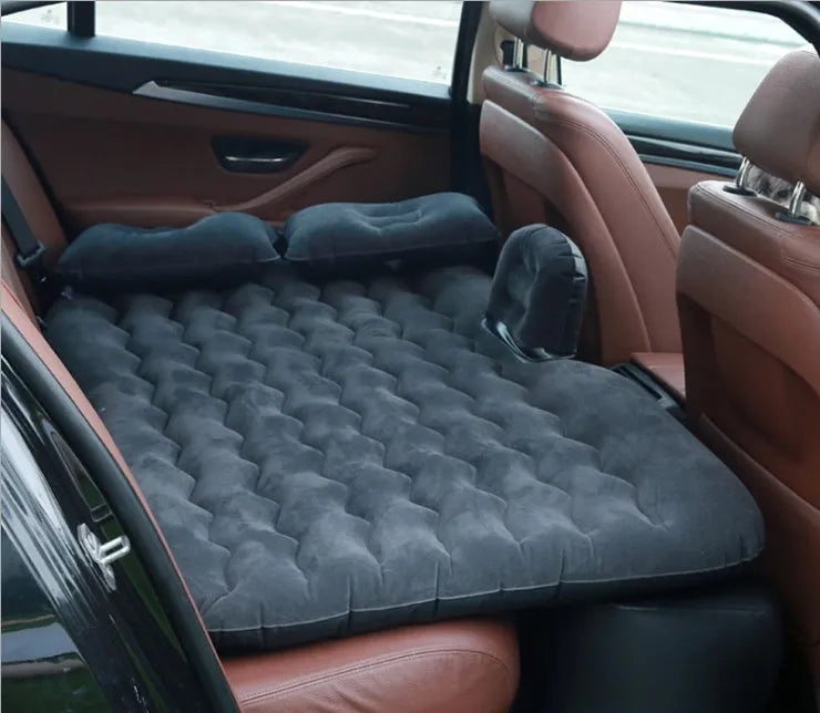 Inflatable car bed with flocked surface folded beside two pillows in storage bag for vehicle sleeping
