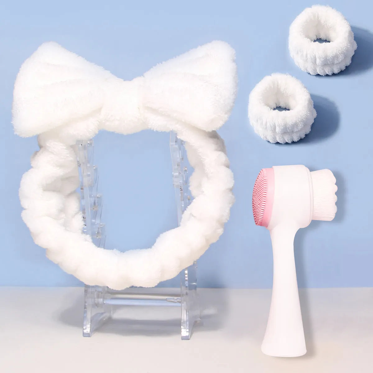 Facial brush and coral fleece hair band set in purple, grey, white, and pink colours.