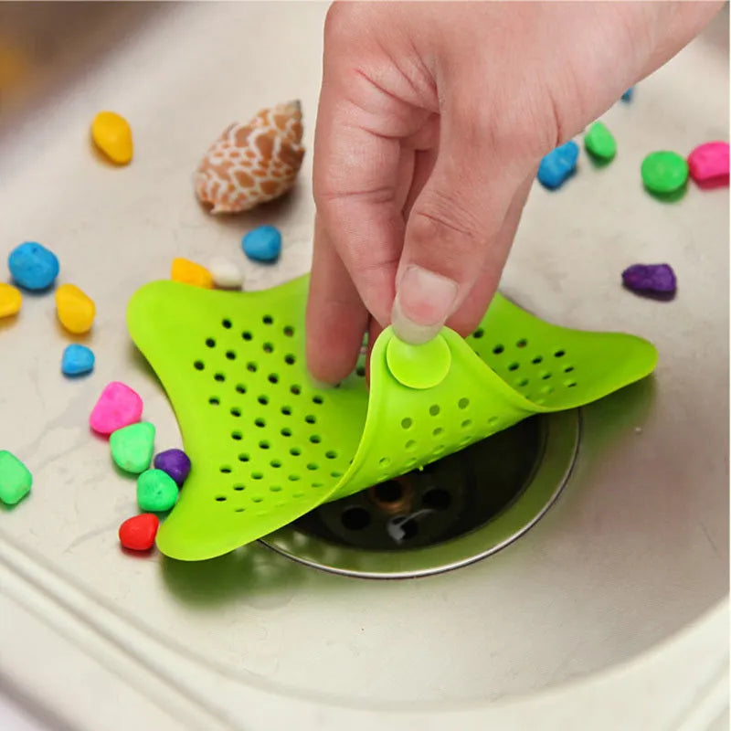 Three starfish-shaped TPR sink drain filters in blue, green, and white on a bathroom sink