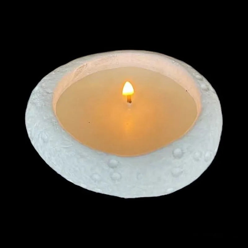 White concrete candle holder on a flat surface with a tea light inside