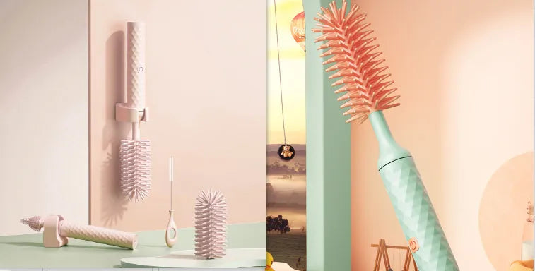 Pink and green electric baby bottle cleaning brush with rotating silicone head on a table