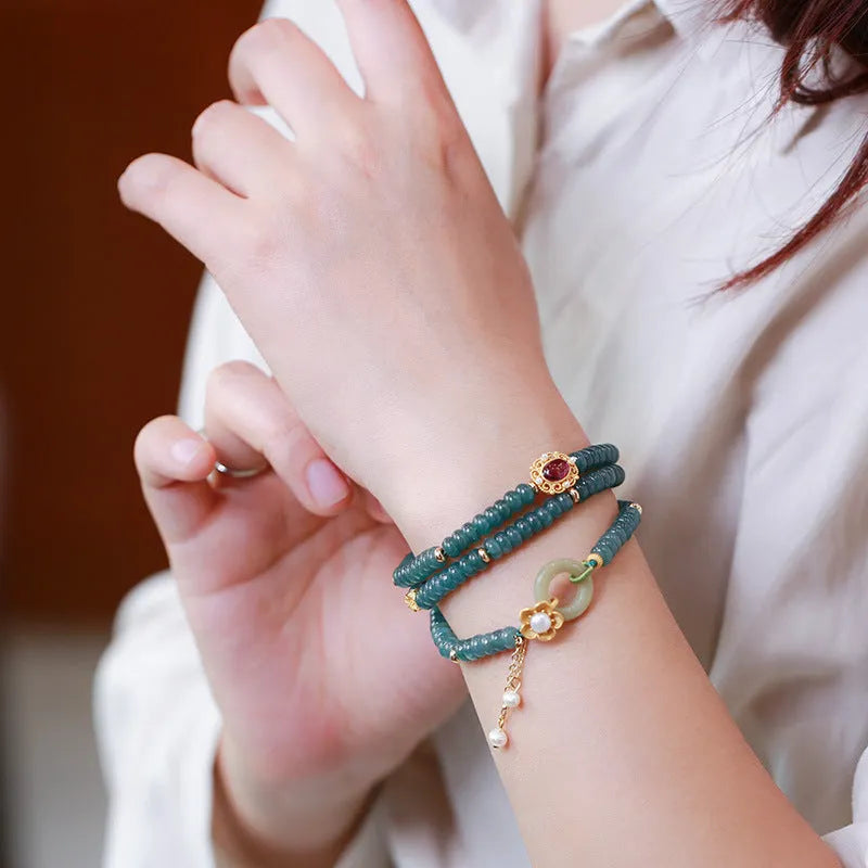 Blue water abacus and jade bead bracelet with tourmaline rings and pearl accents on a wrist.