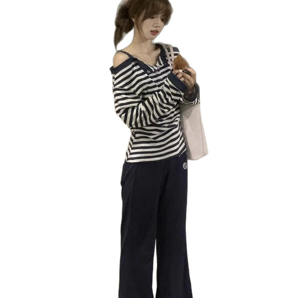Dark blue oversized women's long-sleeved t-shirt with embroidery, stripes, and button detail on a hanger.