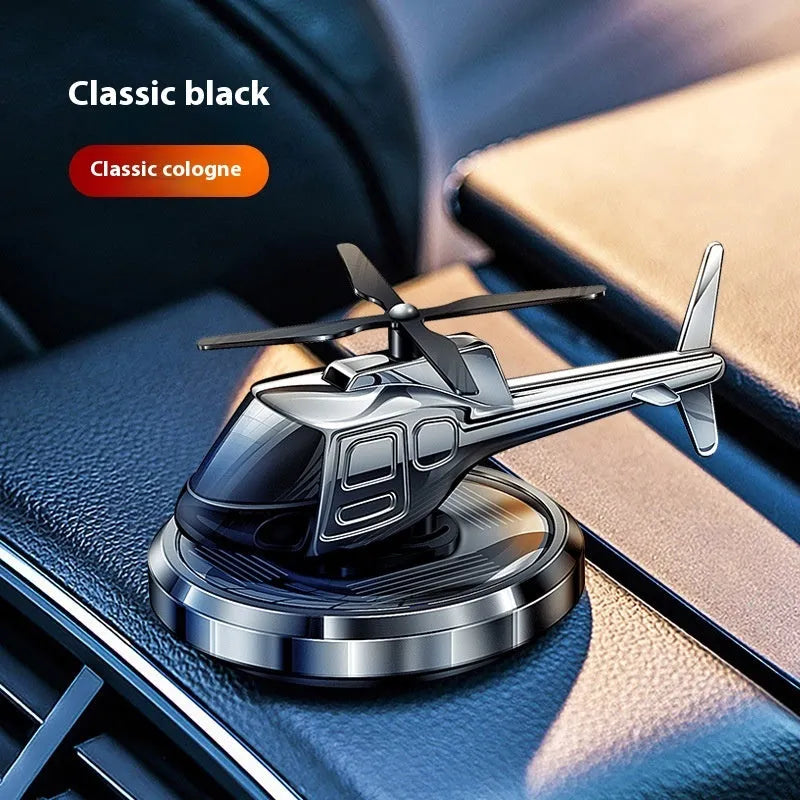 Silver solar-powered rotating metal car air freshener ornament on a dashboard.