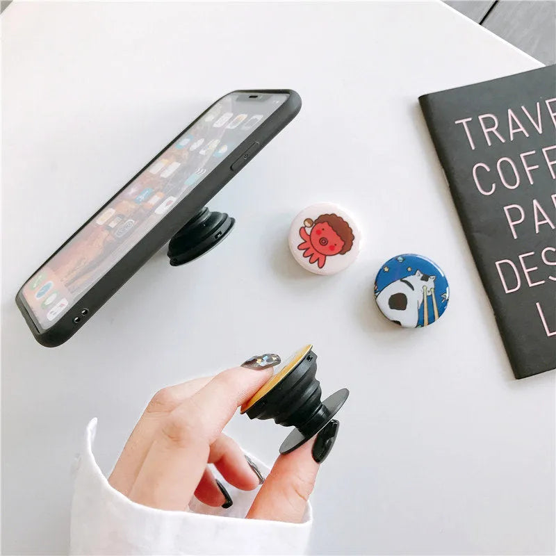 Creative telescopic glue cartoon mobile phone airbag bracket on desktop showing extended arm and cartoon colour design