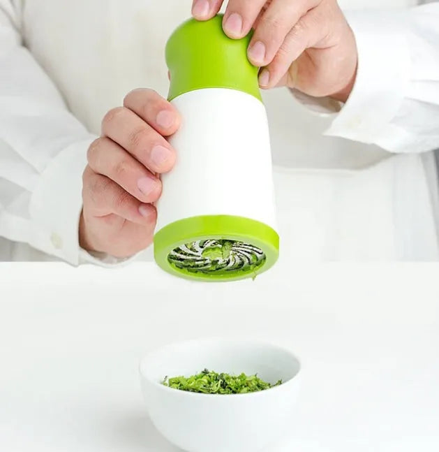 White and silver herb grinder spice mill with removable top on a kitchen counter.