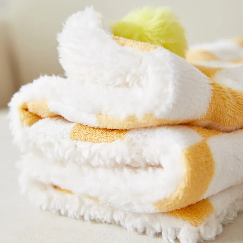 Soft plaid pattern pet blanket with fur ball decoration on a sofa