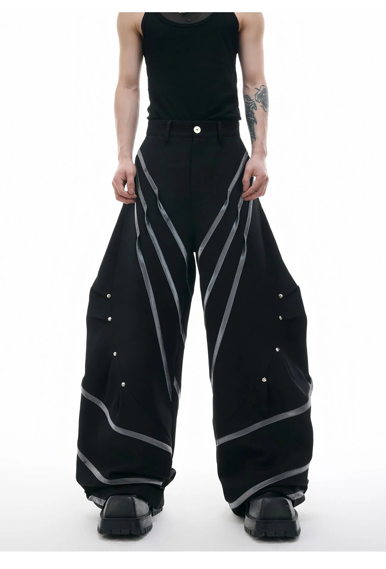 Men's polyester trousers with pleats and metal rivet detailing, shown in black and white colour options.
