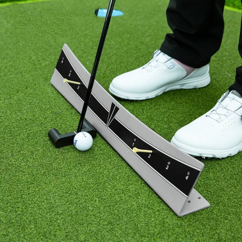 A white PVC golf putter trajectory balance simulator with an adjustable push rod balancer on a grey surface.