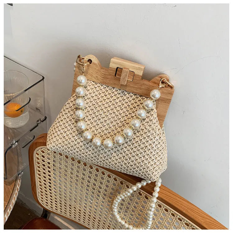 Women's straw woven shoulder bag with pearl chain strap showing interior organisation pockets