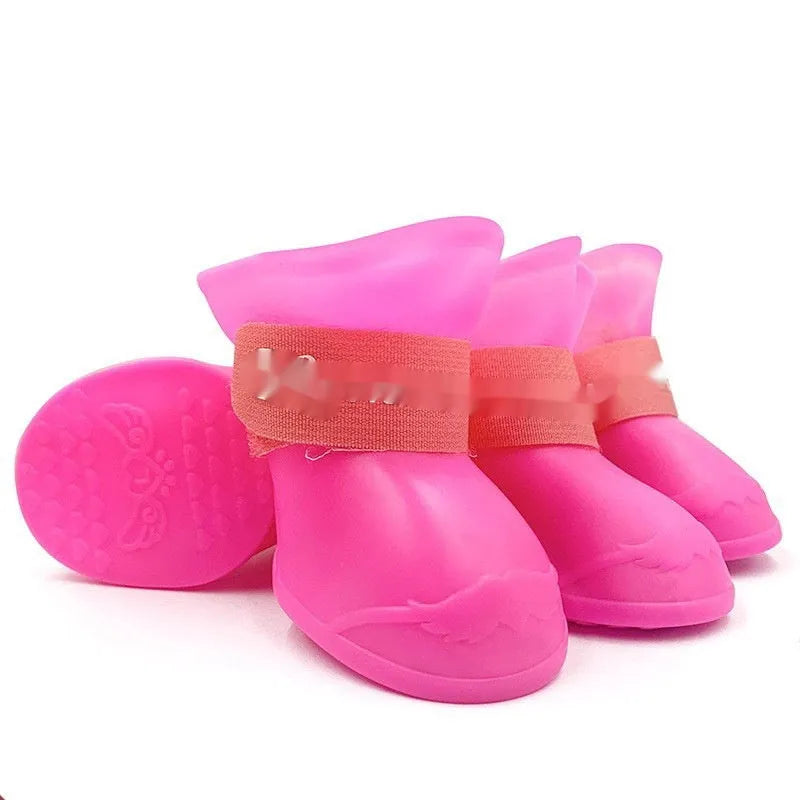 Set of four soft-soled rubber pet rain shoes in assorted colours on a grey background.