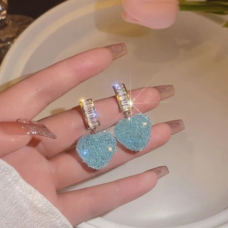 Close-up of women's cute alloy candy stud earrings with a peach heart design in pink and blue.