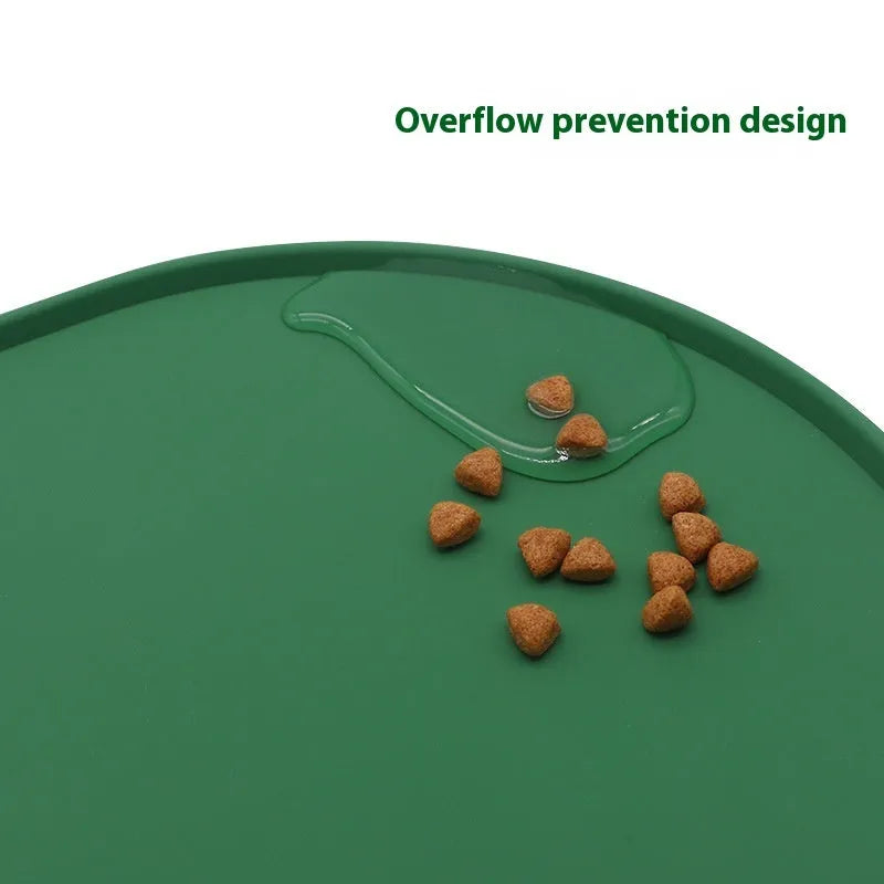Green silicone cat feeding placemat on a floor next to a food bowl.