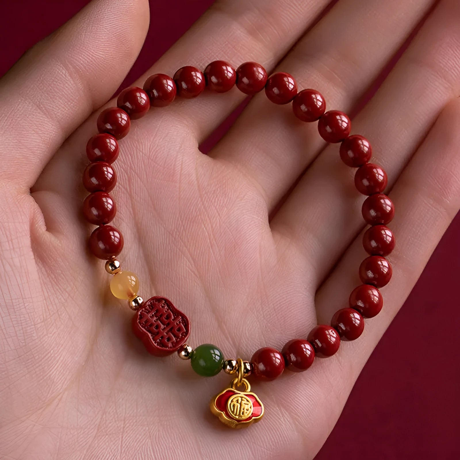 Emperor sandstone bracelet with fu charm on wrist, showing cinnabar and stone beads.