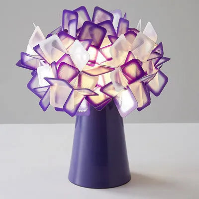 Nordic style decorative table lamp with metal base in a choice of colours on a bedside table.