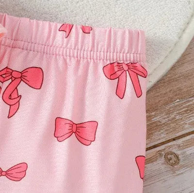 Pink two-piece girls' suit with long sleeve flounced sleeve knitted sweater, printed bow, and flared pants on white background