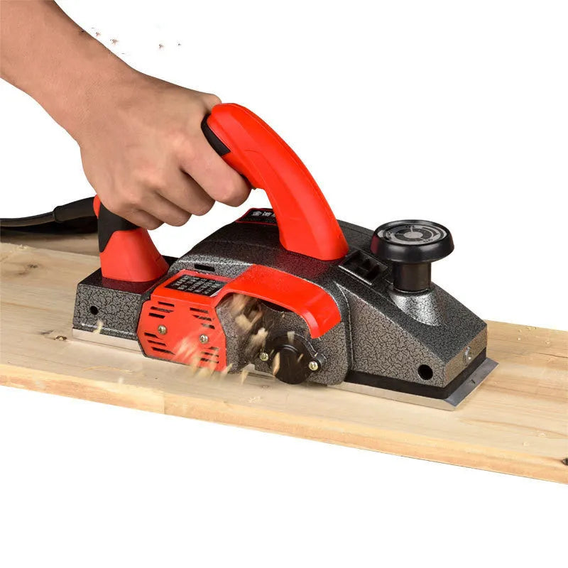 Red desktop electric wood planer with aluminium body, showing 82mm planing width and depth adjustment controls