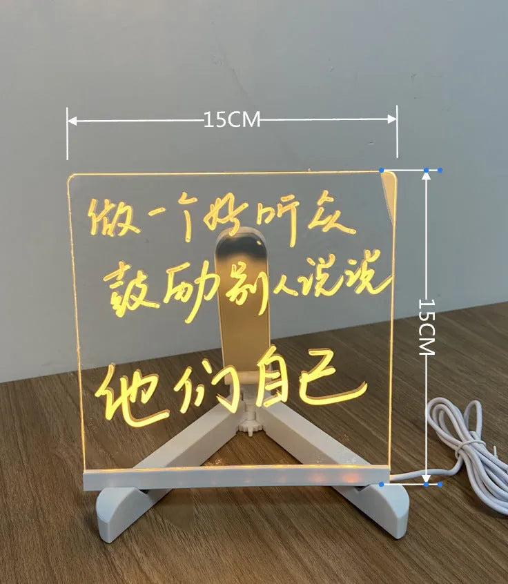DIY acrylic LED message board lamp on a desk with colourful writing, showing USB cable and pens.