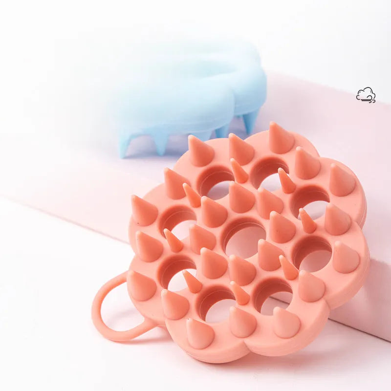 Blue silicone pet grooming brush with soft bristles and an ergonomic massage handle on a white background.