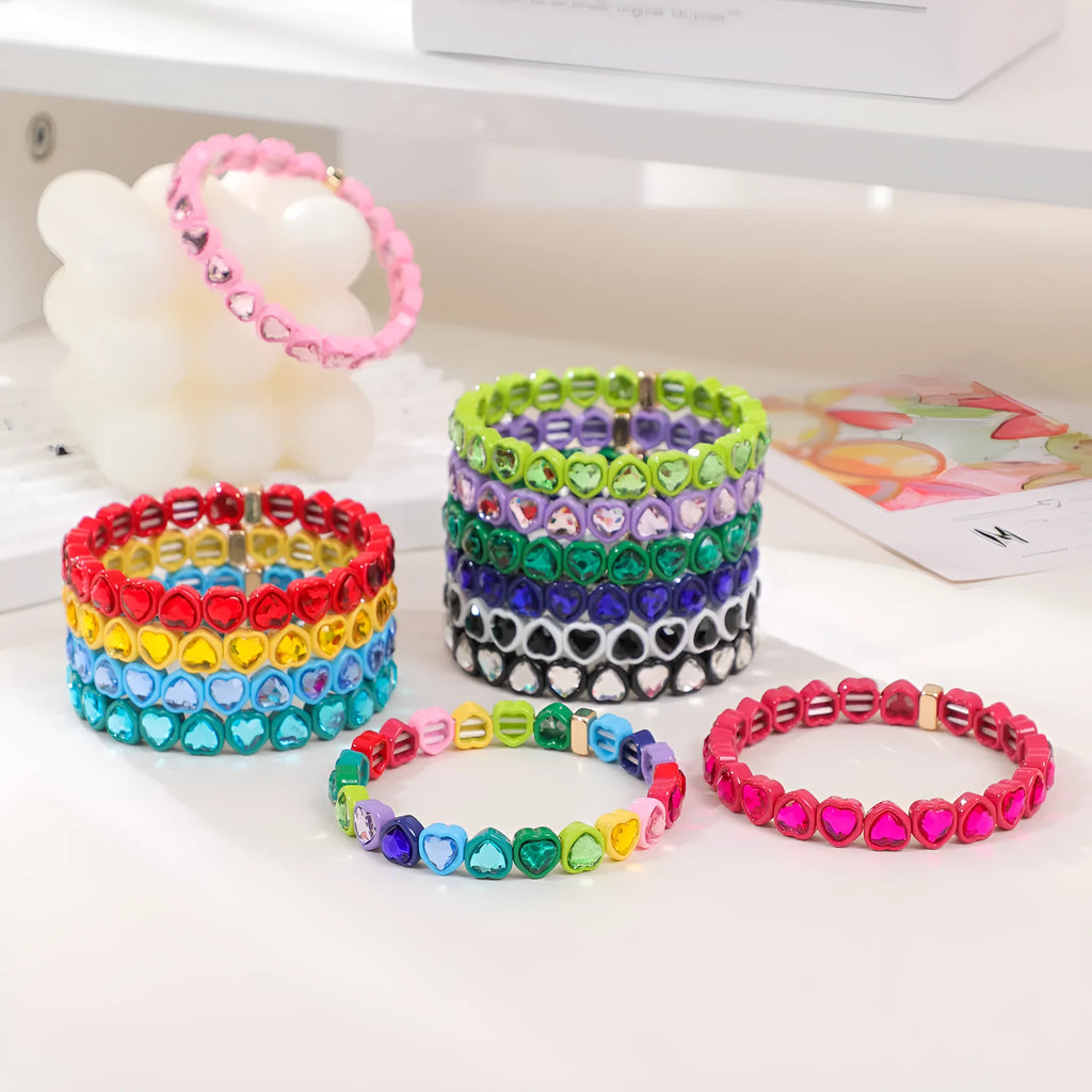 Colourful rainbow enamel heart-shaped stretch bracelet on a wrist.