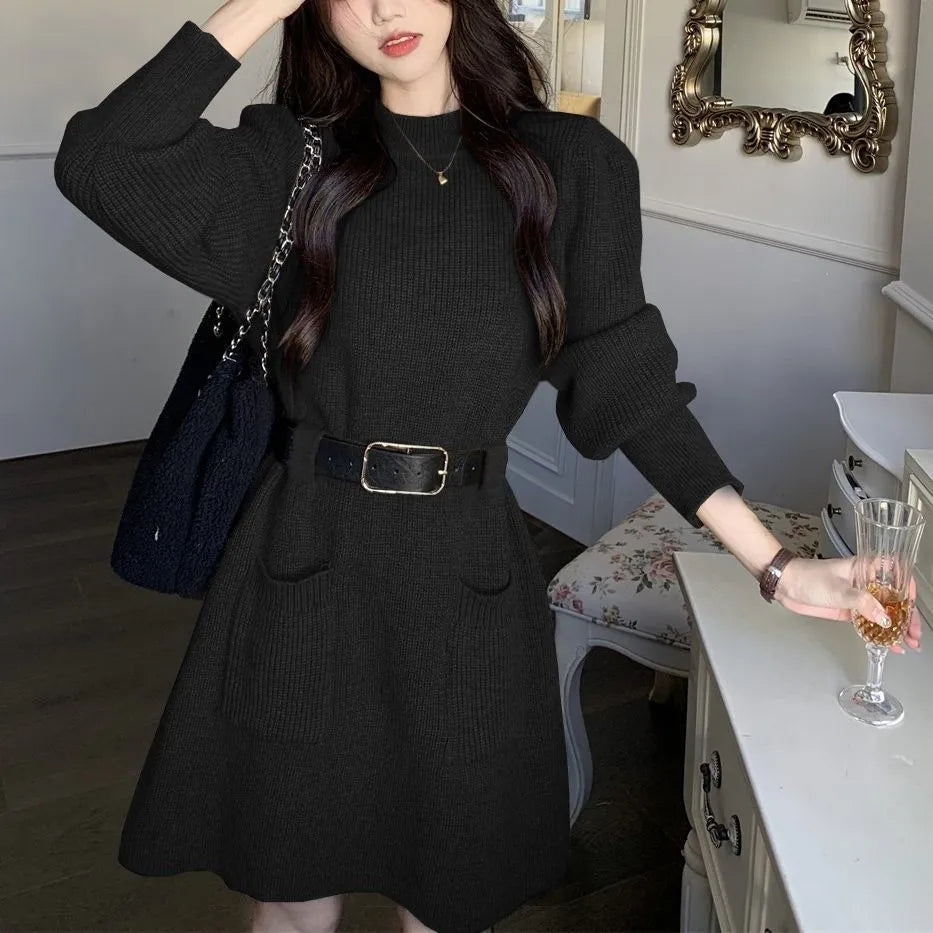 Women's long sleeve loose knitted dress in beige with a black belt, shown on a hanger.