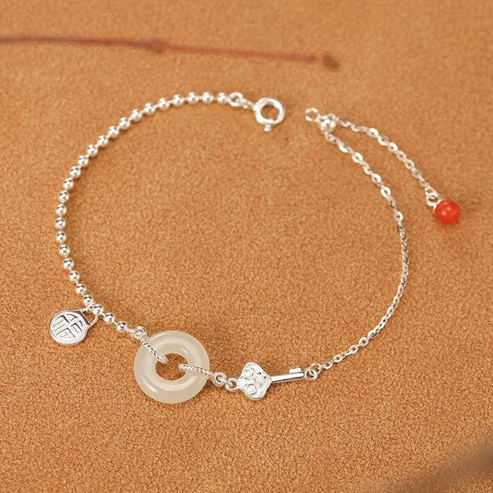 Women's silver bracelet with a geometric Hetian jade Wishful Blessings charm on a white background.