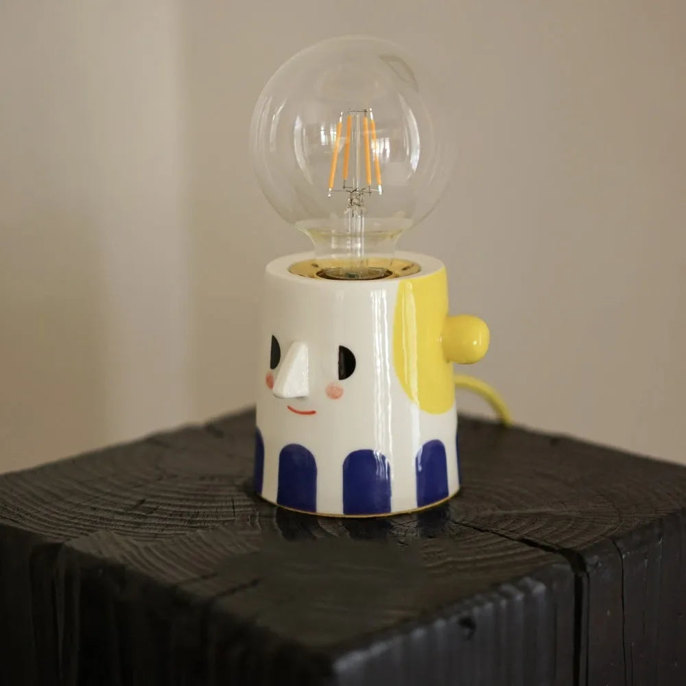 Handmade ceramic table lamp with a white ball headlight shade on a wooden table.