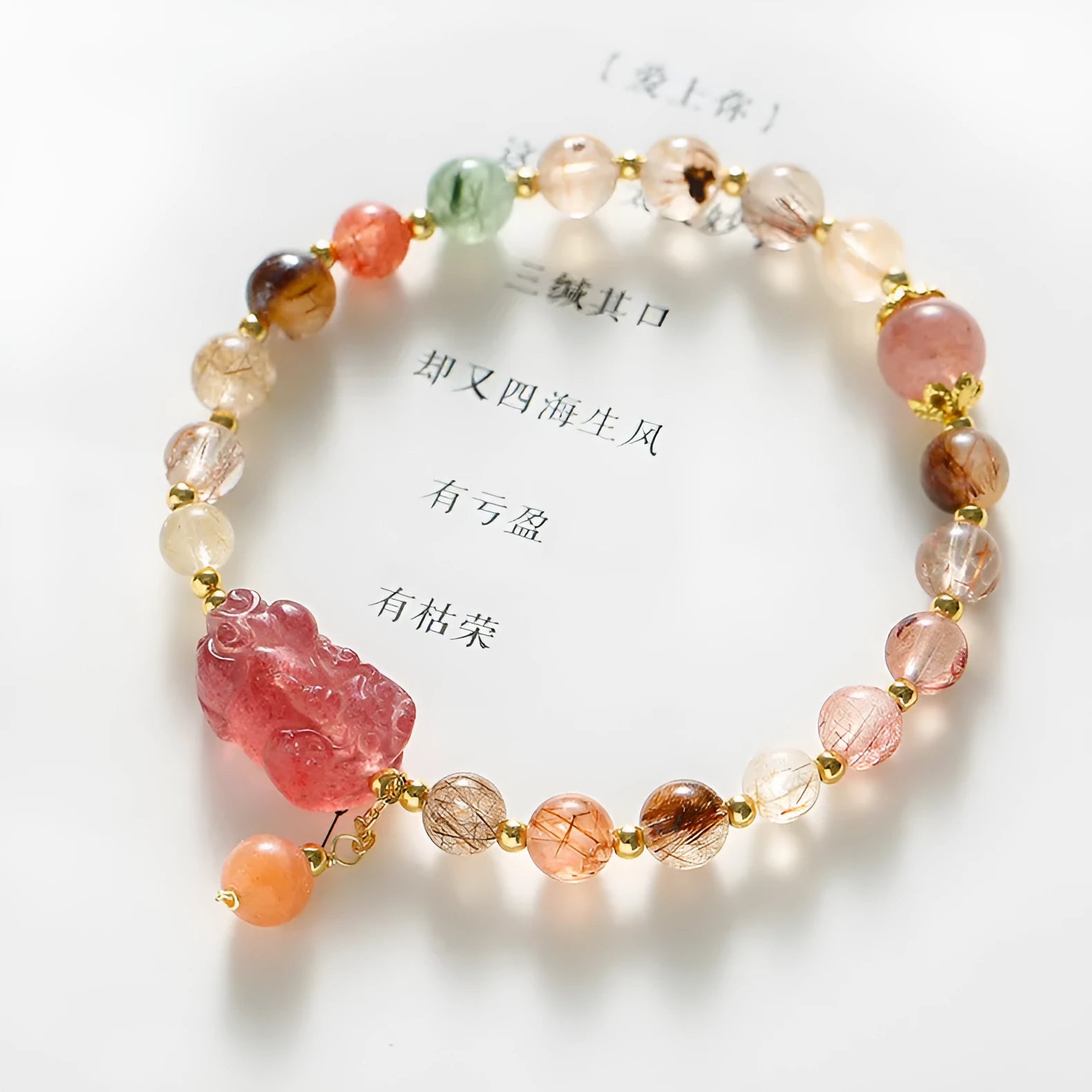 Copper women's bracelet with strawberry quartz crystal, Pixiu charm, and pearl accents on a white background.