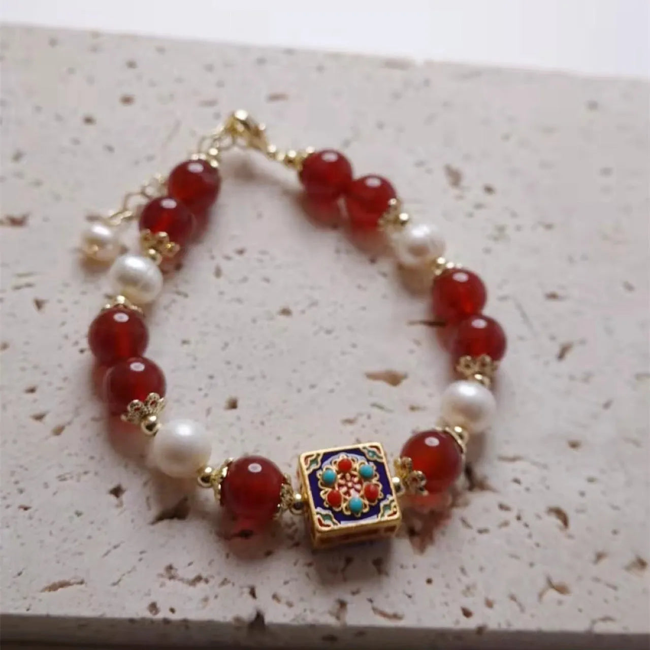 Red agate and pearl women's bracelet with constellation design on a wrist.