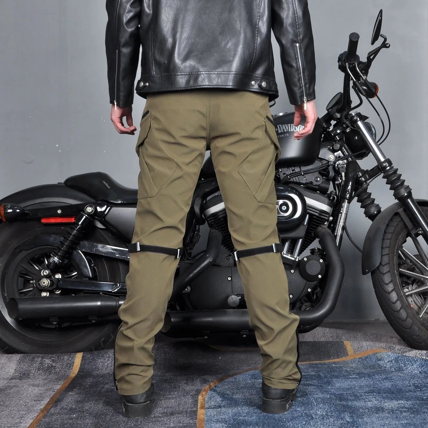 Men's green waterproof motorcycle cycling trousers with belt and protective gear on hanger.