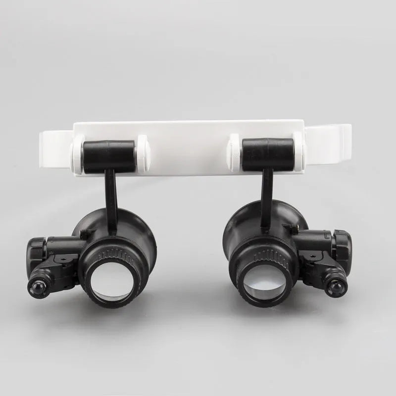 White head mounted magnifying glass with 30 lenses and light on a workbench with circuit board
