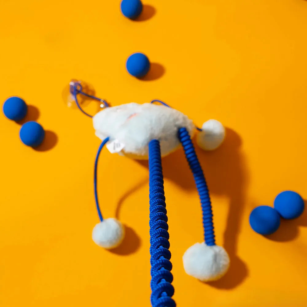Blue plush elastic cat toy with bell in a ring shape on a light background