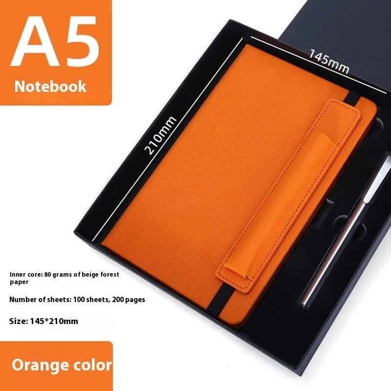 A5 faux leather notebook with pen insert and strap, open on a desk showing lined pages
