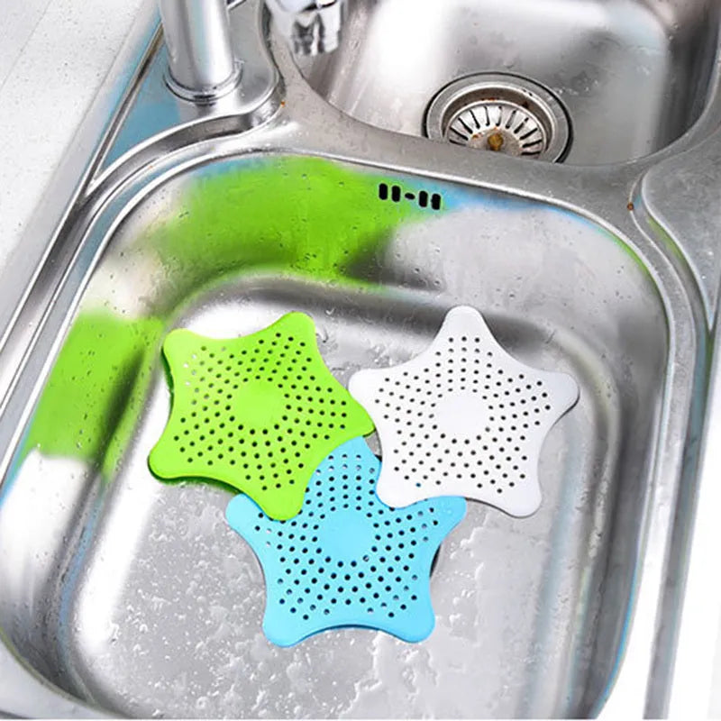 Three starfish-shaped TPR sink drain filters in blue, green, and white on a bathroom sink