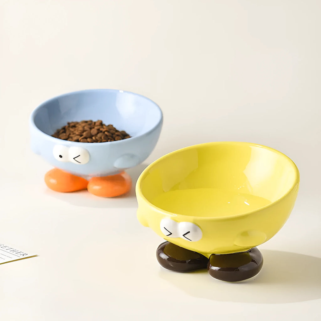 Tall blue ceramic slanted pet bowl with cute expression, designed for cervical spine support.