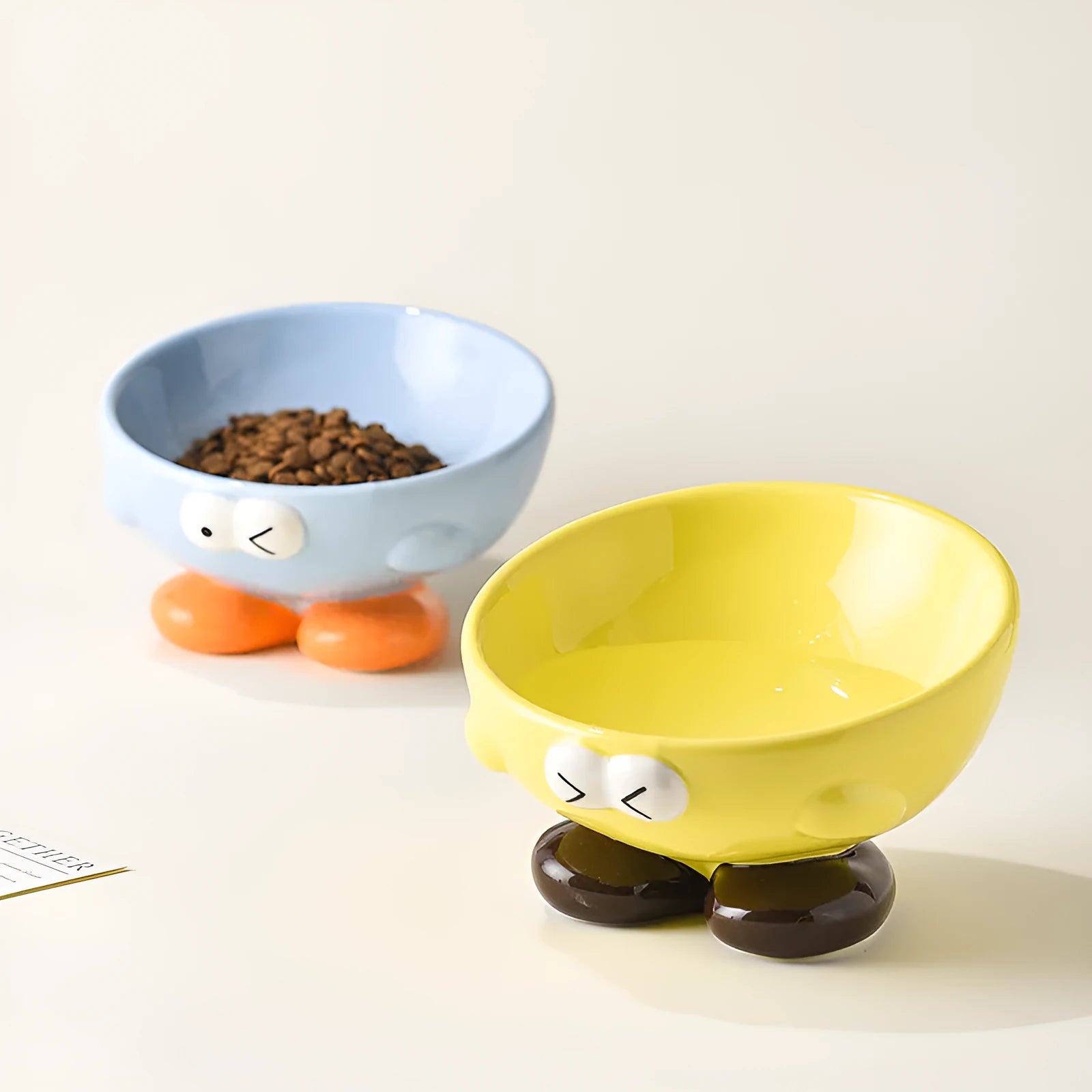 Tall blue ceramic slanted pet bowl with cute expression, designed for cervical spine support.