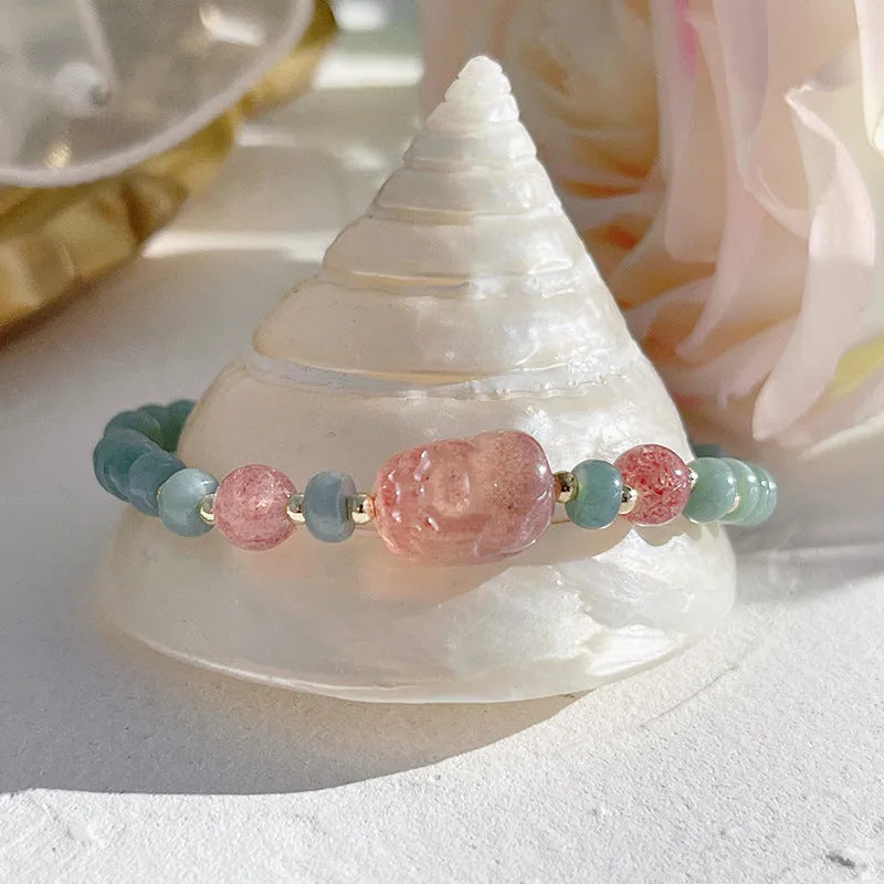 Close-up of a blue jade women's bracelet showing a gourd charm and a peace buckle charm on a string.