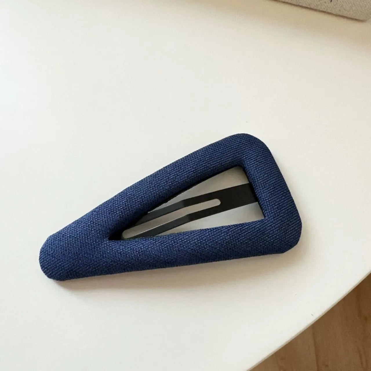 Dark denim barrette with white polka dots in a triangle shape next to a water drop shaped barrette.