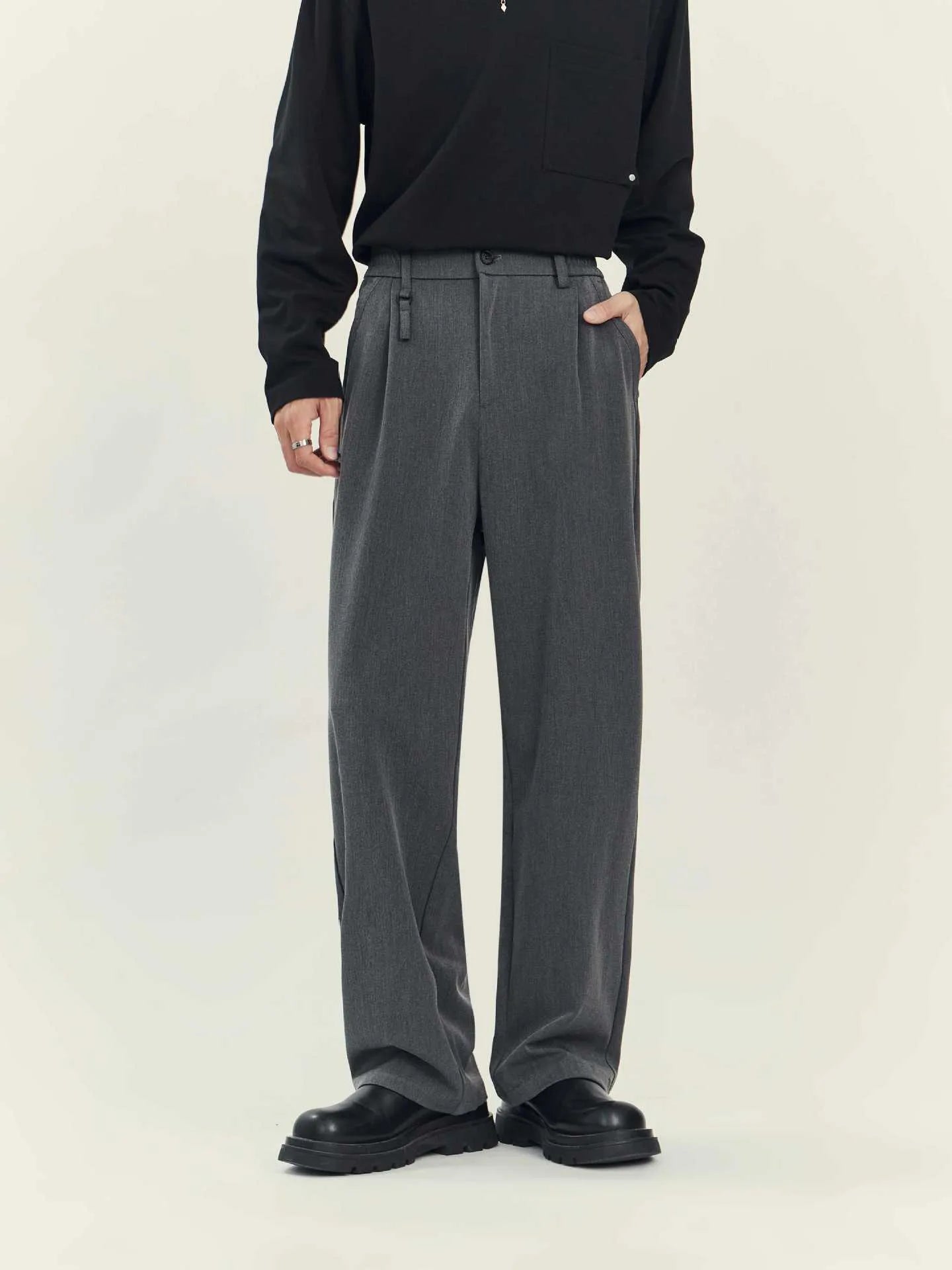 Men's black loose straight-leg business casual trousers on a hanger showing the draping style fit.