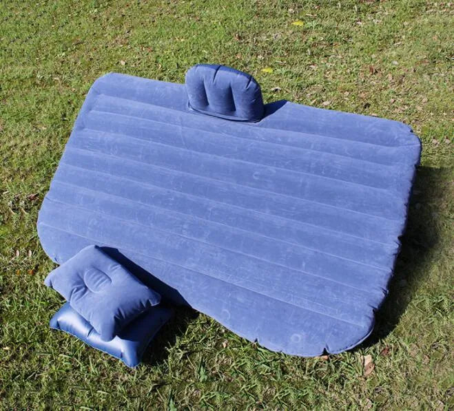 Inflatable car bed with flocked surface folded beside two pillows in storage bag for vehicle sleeping