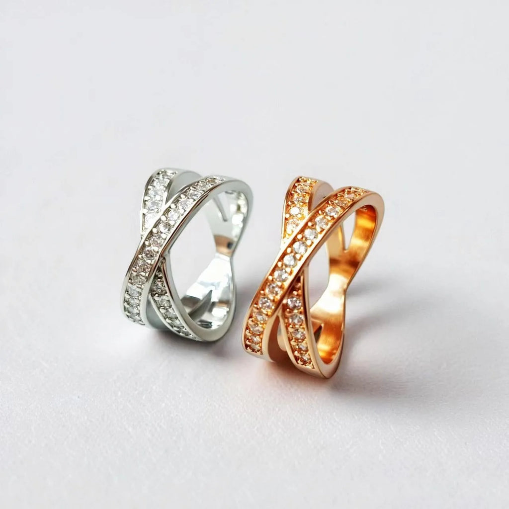Metal ring with cross design and zircon detail in silver or rose gold finish.