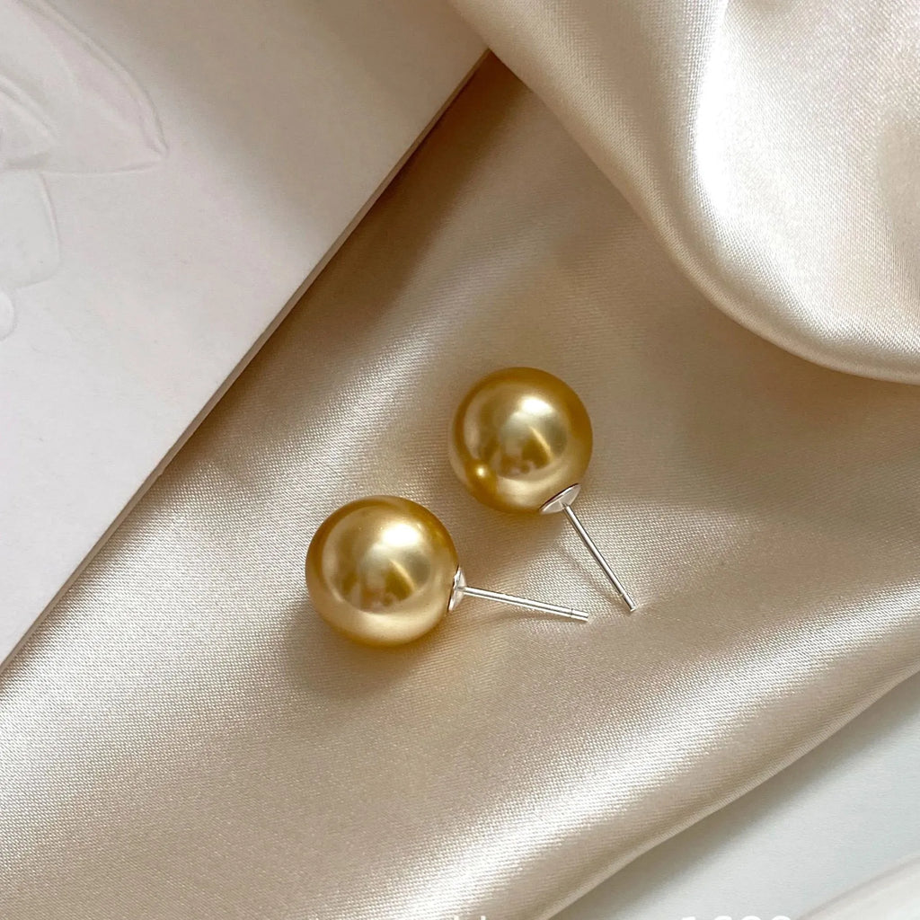 A pair of large pearl stud earrings with a geometric silver setting and an eight-point star detail.