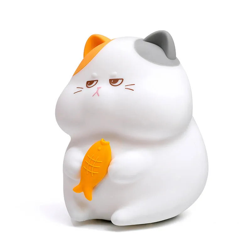 Small yellow Greedy Cat cartoon night light on a desktop, showing fish theme and compact size.