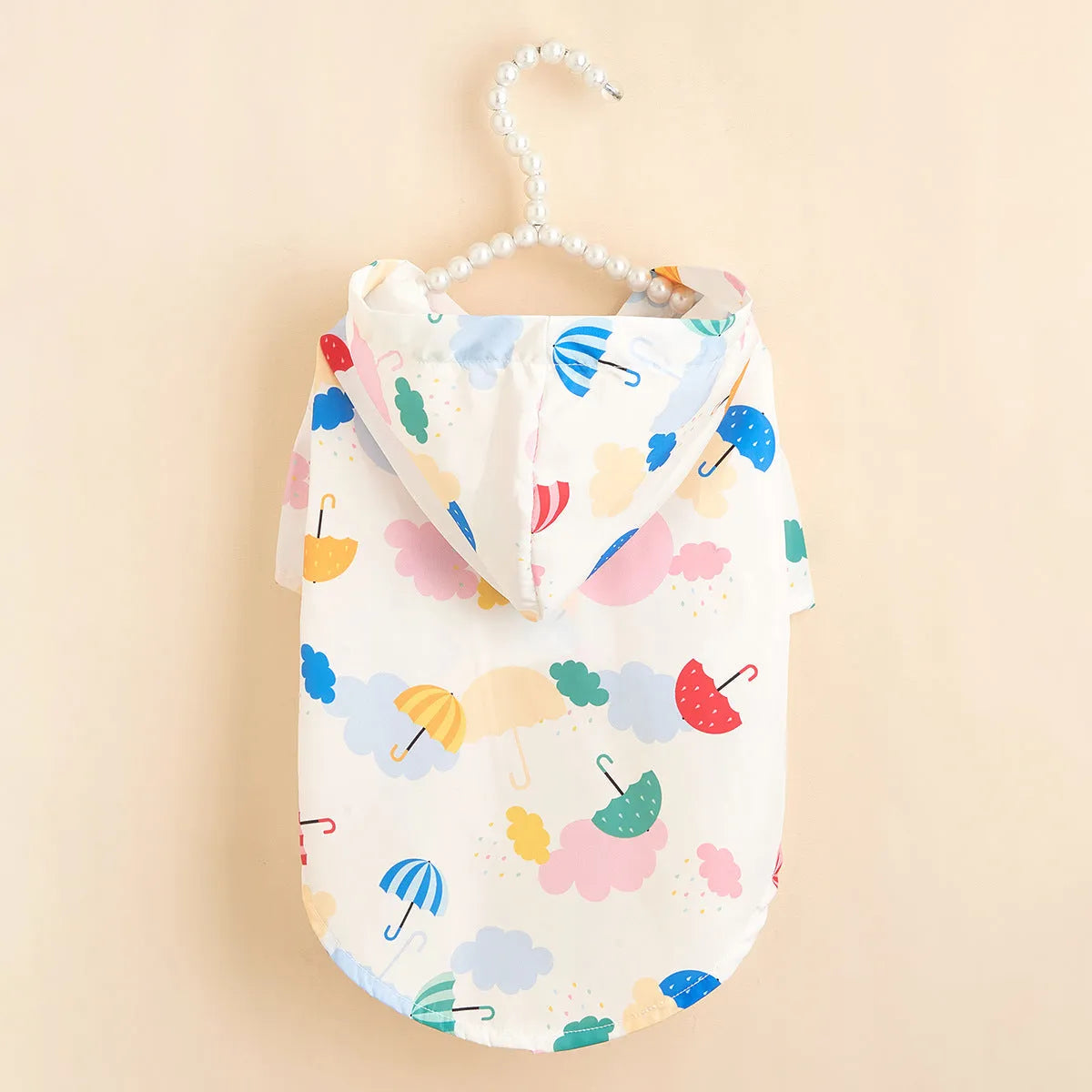 Small dog wearing a colourful cartoon umbrella pattern polyester raincoat.